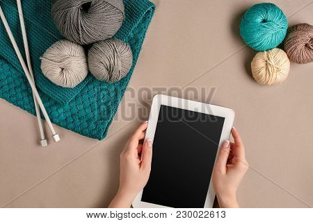 Grey And Turquoise Knitting Wool, Knitting Needles And A Tablet With A Black Screen On Beige Backgro