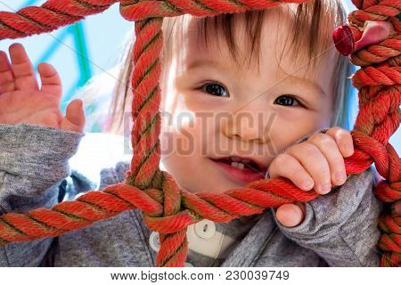 Multracial Toddler Boy Climbing On A Playground Ropes