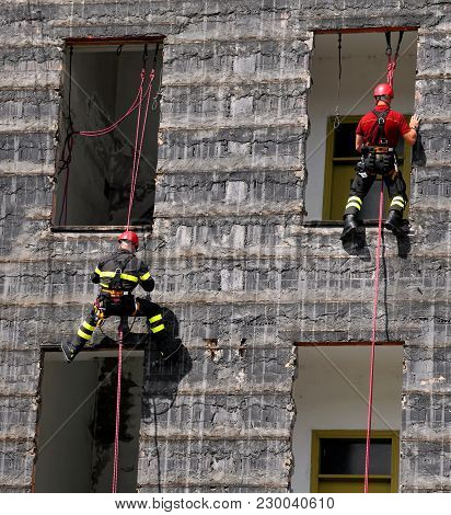 Two Firefighter Climbing A Wall Of A House During The Fire Drill