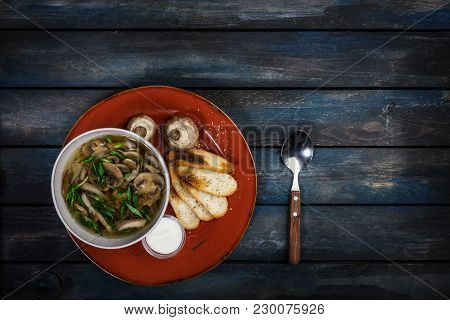 Fresh Mushroom Soup With Green Onion Sour Cream And Bread Crisps. On A Ceramic Plate With A Spoon. C