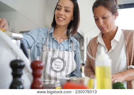Friends cooking together with kitchen robot and tablet