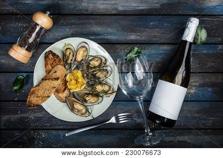 Mussels And Bread Toasts On On A White Plate. Served With Half Grilled Lemon, Fork And Leaves Of Kaf