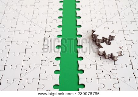 The Green Path Is Laid On The Platform Of A White Folded Jigsaw Puzzle. The Missing Elements Of The 
