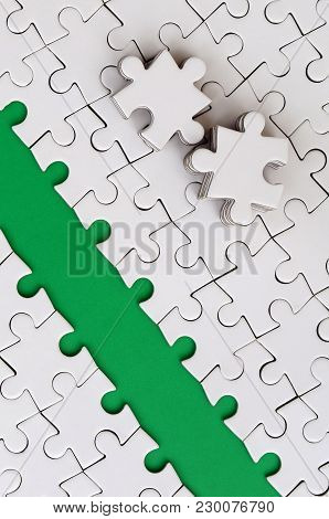 The Green Path Is Laid On The Platform Of A White Folded Jigsaw Puzzle. The Missing Elements Of The 