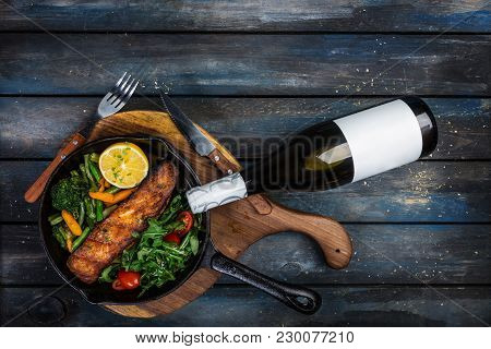 Grilled Salmon Fillet In A Frying Pan, Vegetables, Arugula With A Lemon. Served With Bottle Of Wine 