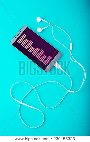 Phone With White Earphones On Blue Background. Concept Of Modern Music And Technology