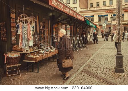Munich, Germany - November 16, 2017: Senior Woman Buying Souvenirs At Market With Handmade Stores On