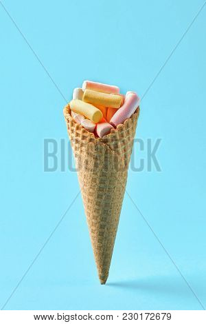 Pink And Yellow Marshmallows In Waffle Cone On Light Blue Background. Top View, Flat Lay. Free Space