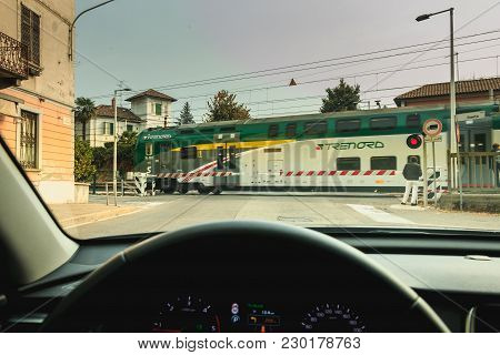 Fino Mornasco, Italy - November 04, 2017 : Driver Watches The Passage Of A Train Behind The Gates Of