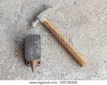 Old Small Hammer And Miniature Anvil With Concrete Background