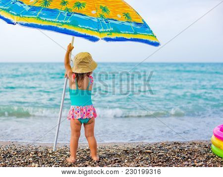 Child On The Beach Under An Umbrella
