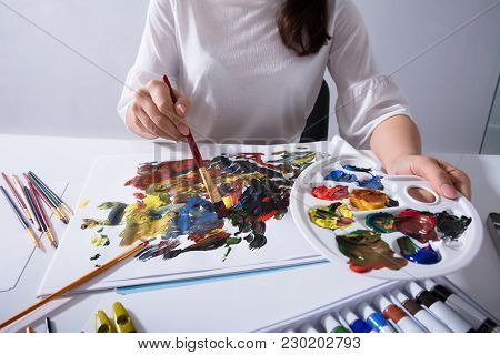 Artist Holding Paint Palette While Painting On Canvas Paper