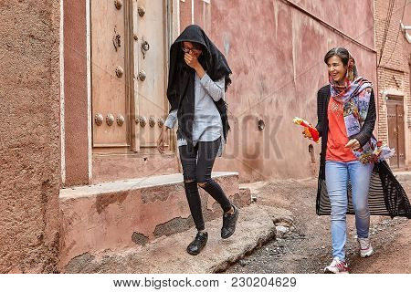 Abyaneh, Iran - April 26, 2017: Two Cheerful Girls-tourists In Hijabs Walk Around The Traditional Vi