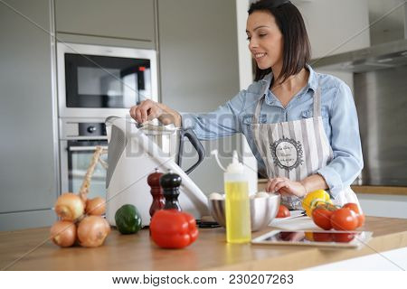 Woman using kitchen robot to prepare dinner
