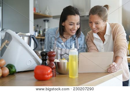 Friends cooking together with kitchen robot and tablet