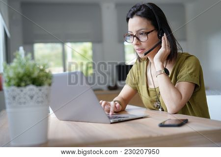 Teleoperator working in office with laptop and headset on