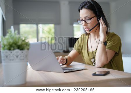 Teleoperator working in office with laptop and headset on