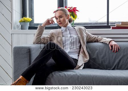 Casual Young Woman In A Brown Jacket Relaxing In A Room With Wondow.