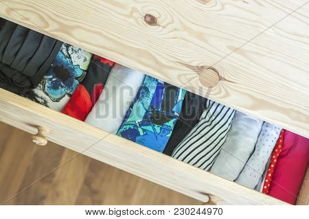 Open Light Wooden Dresser Drawer With Colorful Clothes.