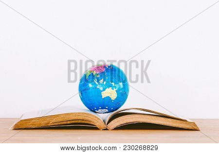 Global Ball On Book On Wooden Table