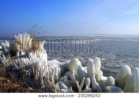 Ice Drip On Dutch Lakeside During Winter. In The Background The City Of Almere Haven And Gooimeer.