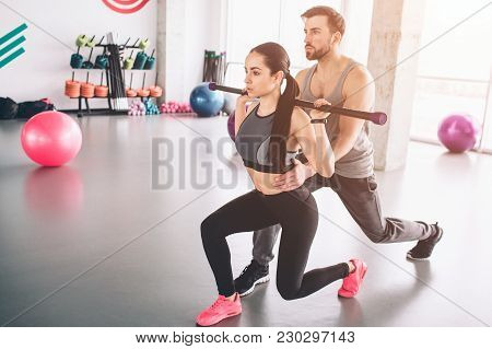 Well-built And Strong Trainer Ih Helping Beautiful And Slim Girl To Do Some Attacks Carrying Bodybar