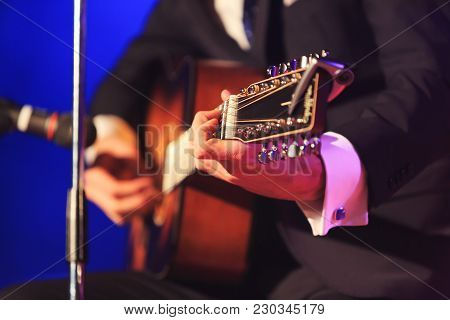 Singer With Guitar Playing Pop Or Classic Music On A Colorful Fancy Background. Singer In Elegant Co