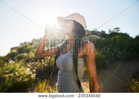 fit female hiker taking a break to drink water from waterbottle