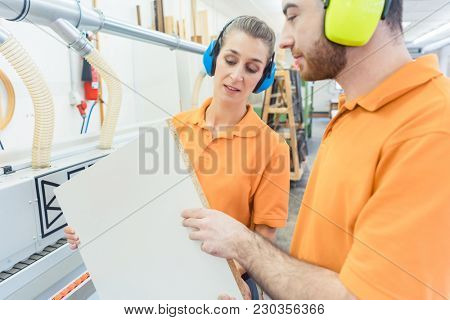 Carpenter in furniture factory inspecting piece in QA being satisfied 