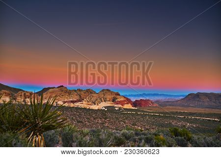 sun setting over redrock canyon rocks with las vegas in background