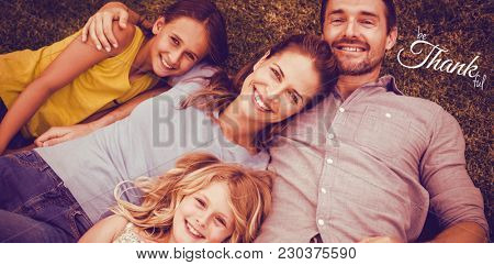 Digital image of happy thanksgiving day text greeting against portrait of happy family lying on field