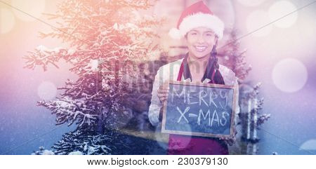 Snow covered trees during winter against pretty waitress with merry x-mas written on chalkboard