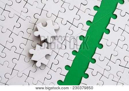 The Green Path Is Laid On The Platform Of A White Folded Jigsaw Puzzle. The Missing Elements Of The 