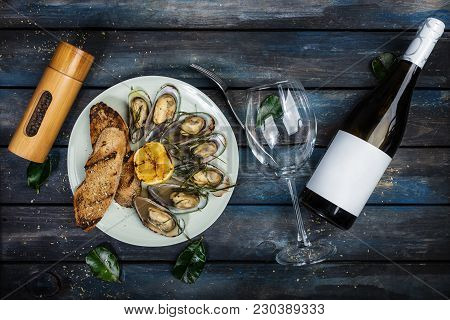 Mussels And Bread Toasts On On A White Plate. Served With Half Grilled Lemon, Fork And Leaves Of Kaf