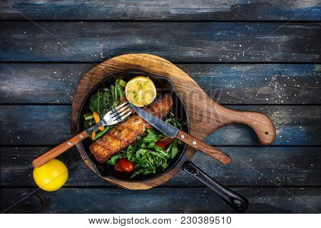 Grilled Salmon Fillet In A Frying Pan, Vegetables, Arugula With A Lemon. On The Cutting Board And Wo