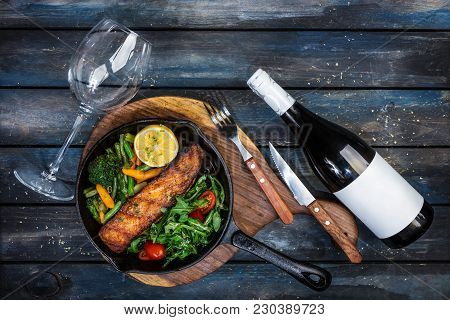 Grilled Salmon Fillet In A Frying Pan, Vegetables, Arugula With A Lemon. Served With Bottle And Glas