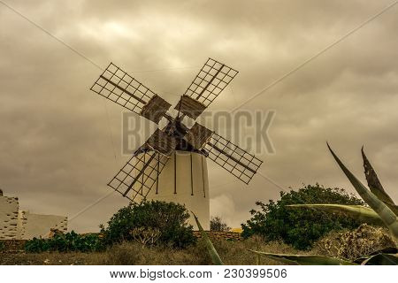Spanish Windmill Made Of Stone With Blue Sky And Dark Clouds