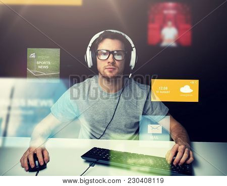 technology, communication, mass media, virtual reality and people concept - young man in headset and eyeglasses with pc computer keyboard over virtual screens