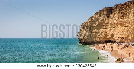 CARVOEIRO, PORTUGAL - AUGUST 27, 2016: Tourists relaxing on sandy beach near Carvoeiro in Portugal