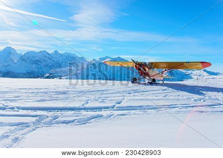 Mannlichen, Switzerland - December 31, 2013: Yellow Airplane At Mountain Peaks In Mannlichen In Wint