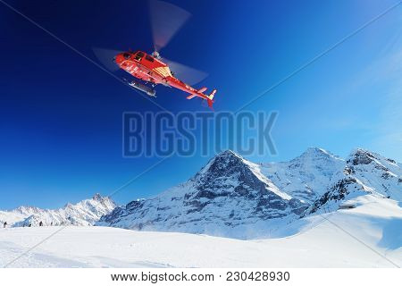 Mannlichen, Switzerland - December 31, 2013: Red Helicopter Flying, At Swiss Alpine Mountain Mannlic