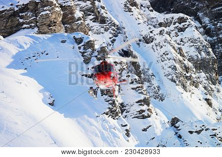 Mannlichen, Switzerland - December 31, 2013: Red Helicopter Flying At Swiss Alpine Mountain Mannlich