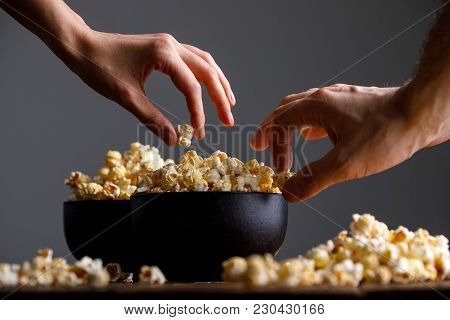Hands Reach For A Bowl With Tasty Popcorn.