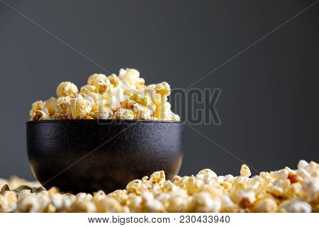 Popcorn In A Black Ceramic Cup And Around It.