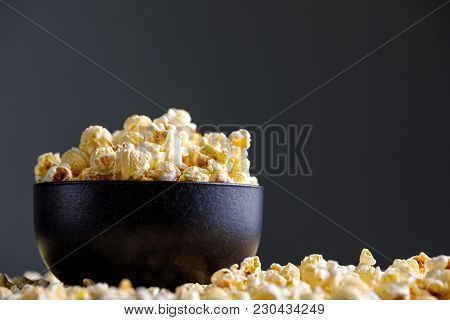 Popcorn In A Black Ceramic Bowl And Around It.