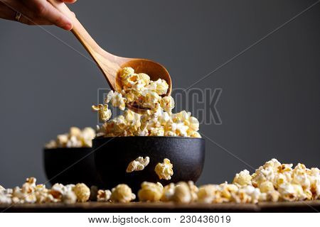 Popcorn Falls From A Wooden Spoon Into The Cups And Around Them.