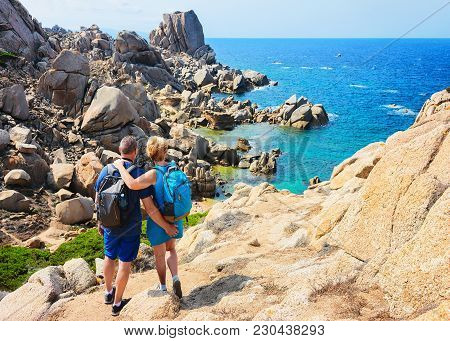 Couple Looking At The Sea And Rocks In Capo Testa, Santa Teresa Gallura, Sardinia, Italy