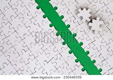 The Green Path Is Laid On The Platform Of A White Folded Jigsaw Puzzle. The Missing Elements Of The 