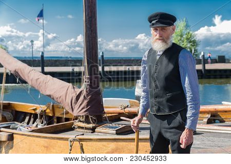 Urk, The Netherlands - September 02, 2017: Old Sailor With Stick, Cap And Beard Standing For Traditi