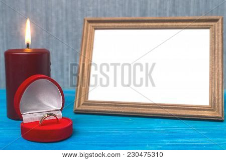 Wedding Ring In A Gift Present Box And Empty Photo Frame Of A Loved One Copy Space And Burning Candl